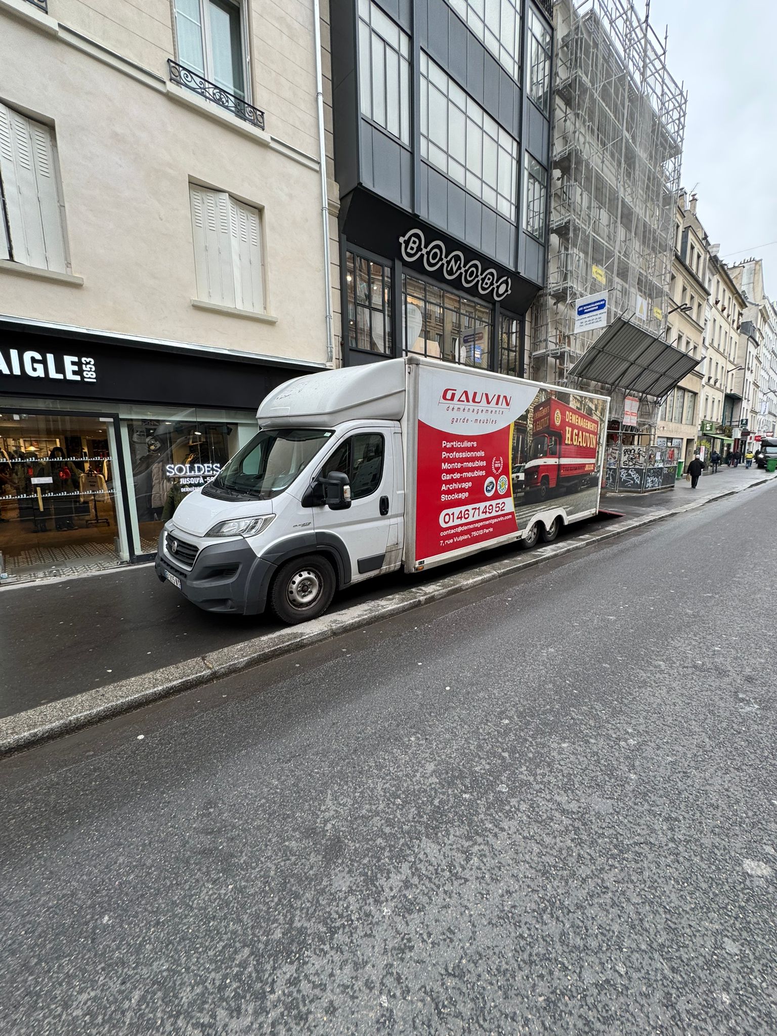Balisage de sécurité avec cônes et ruban pour installation de monte-meuble sur la voie publique à Paris.