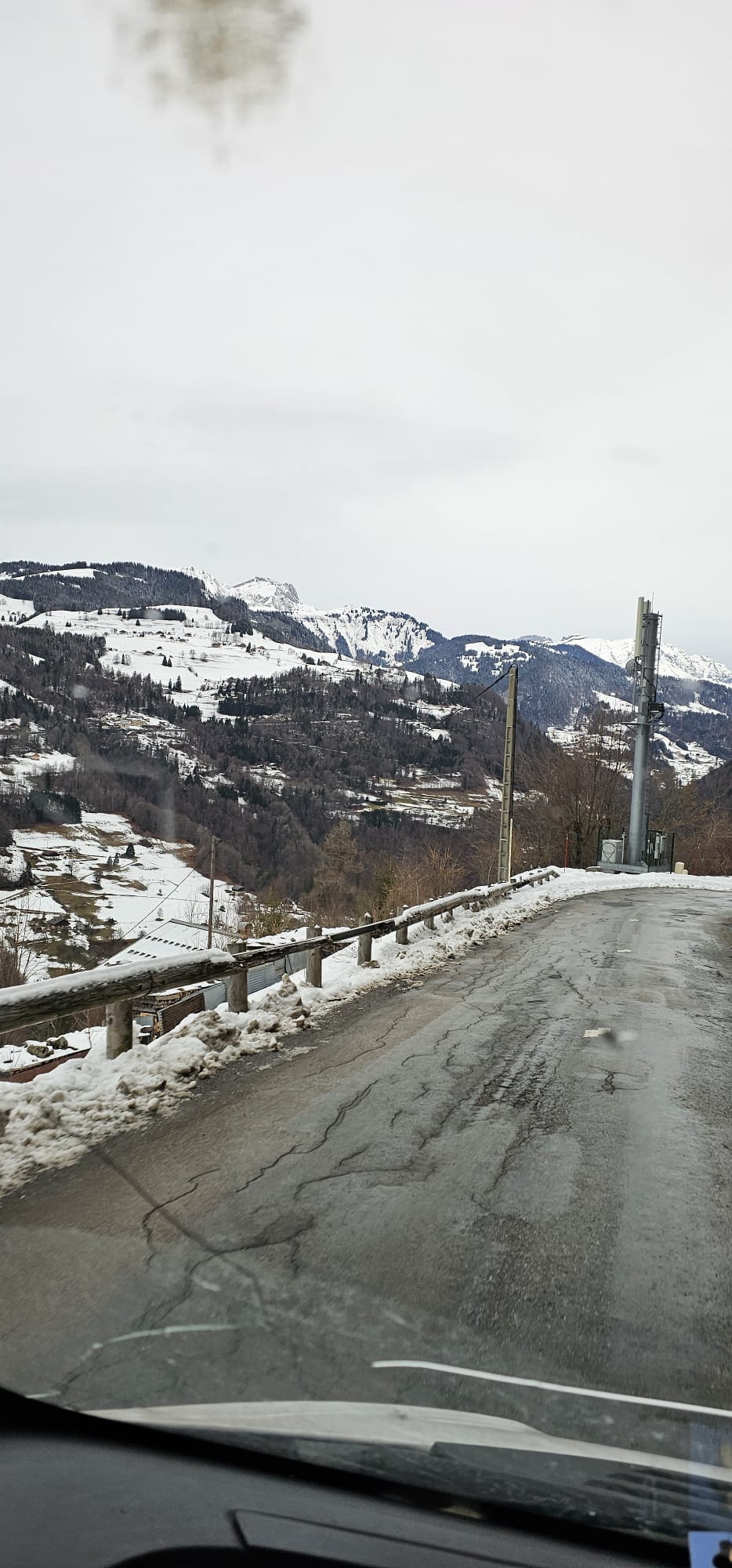 Route de montagne sinueuse et enneigée vue depuis le pare-brise d'un véhicule de transport routier, illustrant la maîtrise des trajets difficiles.