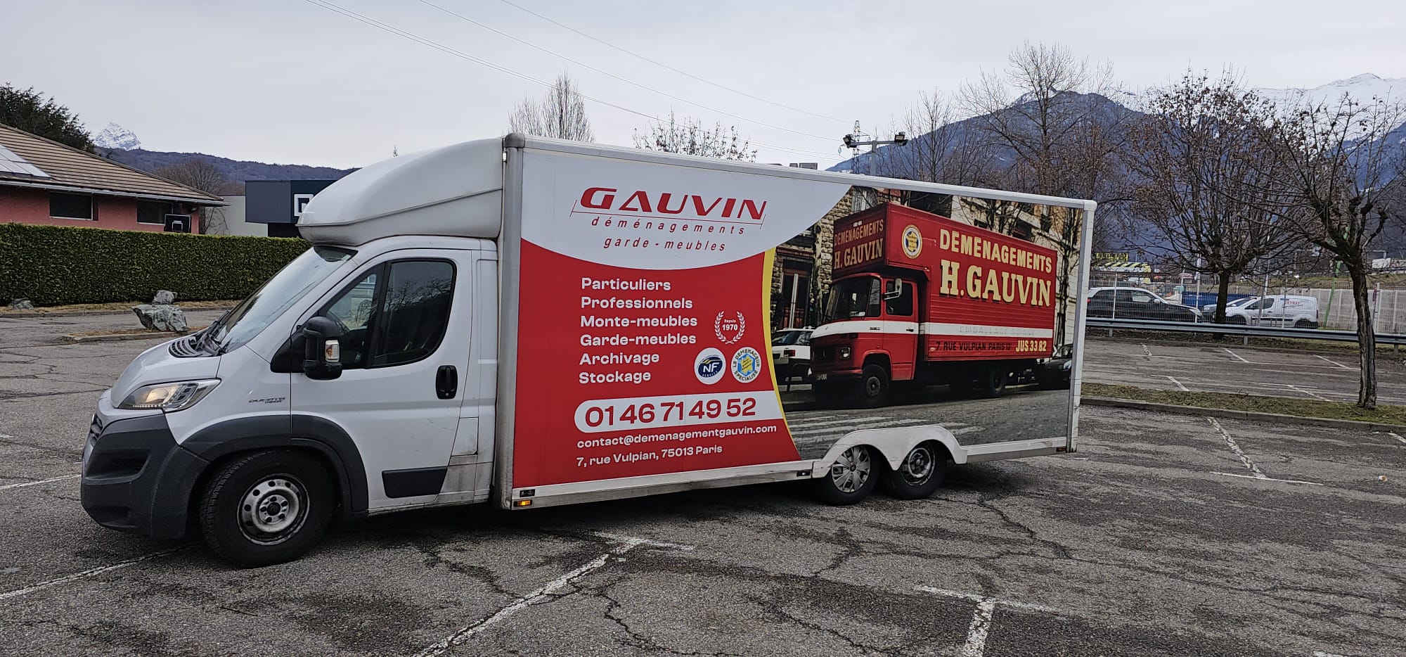 Plan rapproché du camion utilitaire H. Gauvin affichant les services de garde-meubles et déménagement, devant un majestueux massif montagneux enneigé.