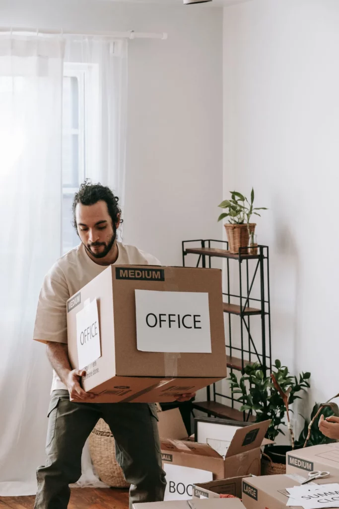 Déménageur portant une pile de cartons de bureaux